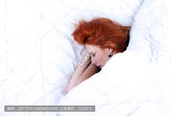 美麗的年輕女子睡在白色被褥