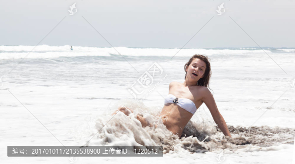 美麗的女孩在海岸上的海灘上曬黑