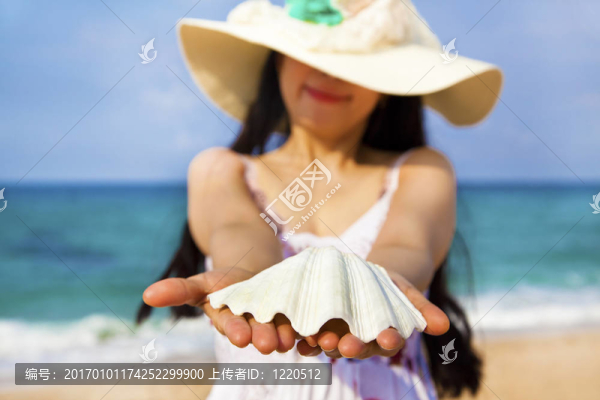 微笑的年輕女子在海灘上拿著貝殼