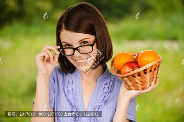 年輕快樂的女人戴著眼鏡拿著水果籃子