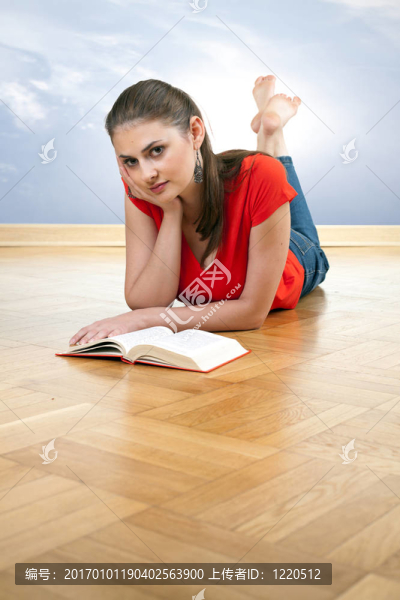 躺在木地板上的年輕女子讀書