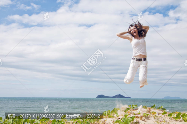 迷人的女子跳在熱帶海灘的喜悅