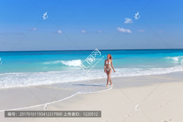 年輕女子走在海邊的海灘上