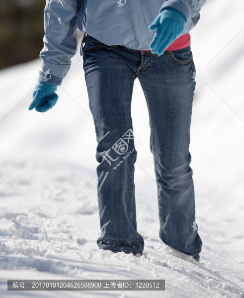 一個美麗的年輕女子在一個陽光明媚的冬日里走在厚厚的雪地上