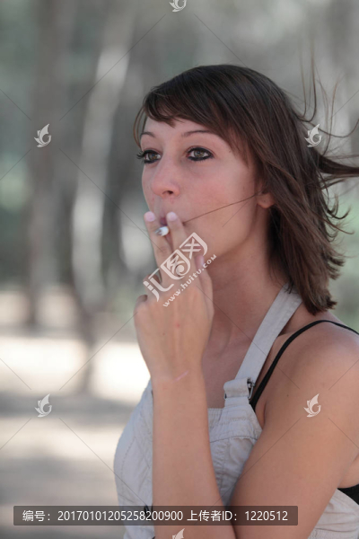 一個(gè)漂亮的年輕女人在戶外點(diǎn)燃香煙的肖像