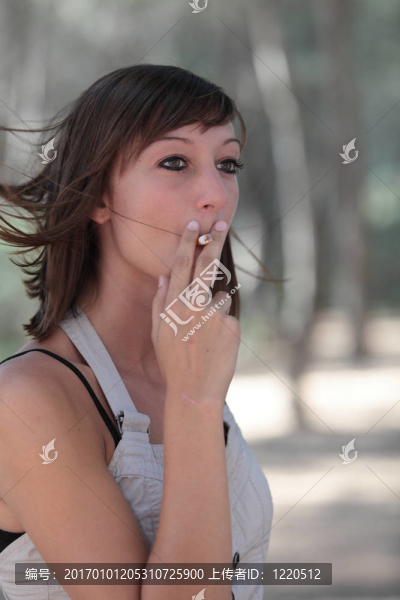 一個(gè)漂亮的年輕女人在戶外點(diǎn)燃香煙的肖像