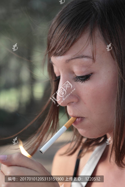 一個(gè)漂亮的年輕女人在戶外點(diǎn)燃香煙的肖像