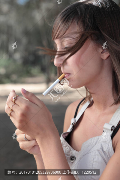 一個漂亮的年輕女人在戶外點燃香煙的肖像