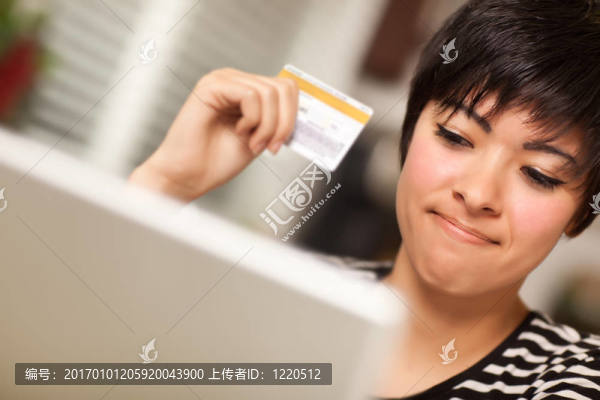 微笑多民族的女子拿著信用卡使用的筆記本電腦