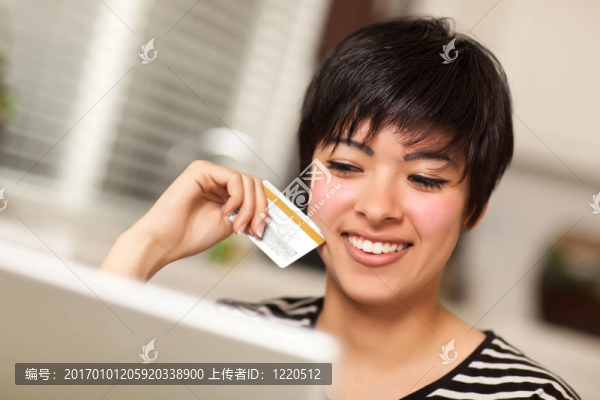 微笑多民族的女子拿著信用卡使用的筆記本電腦