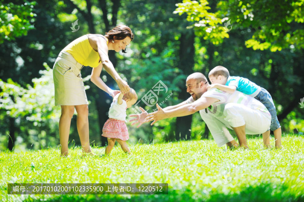 快樂的年輕夫婦和他們的孩子在公園玩得開心