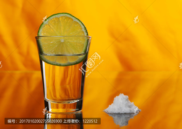 龍舌蘭酒在玻璃一片檸檬和一堆的橙色背景上的副鹽（選擇重點(diǎn)）
