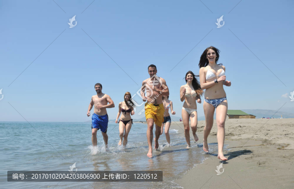 快樂(lè)人團(tuán)體在海灘上玩樂(lè)和跑步