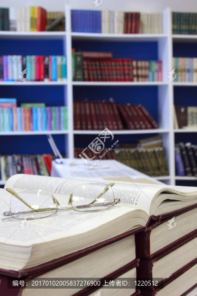 在圖書館書架的背景打開的書和眼鏡