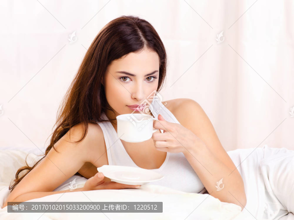 在床上抱著一杯咖啡的女人