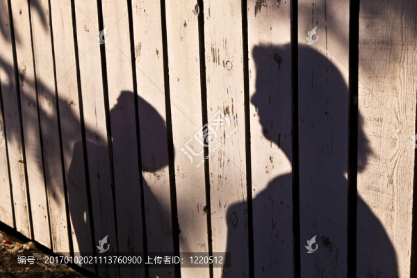 一個(gè)男孩和母親在木制籬笆上的影子