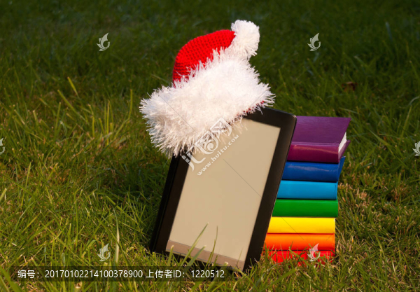 電子圖書閱讀器戴圣誕老人的帽子與堆棧的書籍