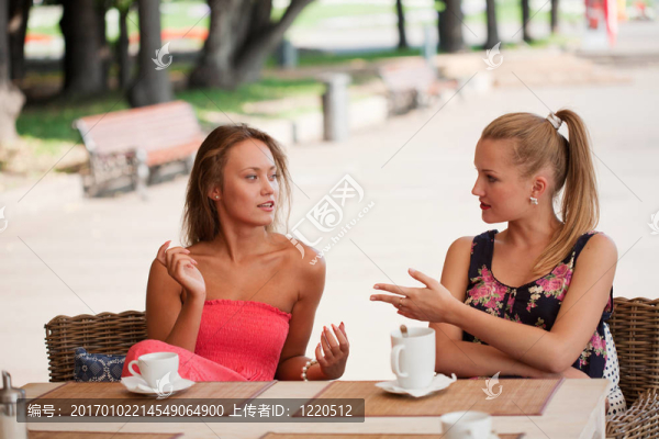 漂亮的女孩在公園的街頭咖啡館休息
