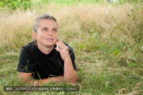 中年婦女用手機躺在草地上