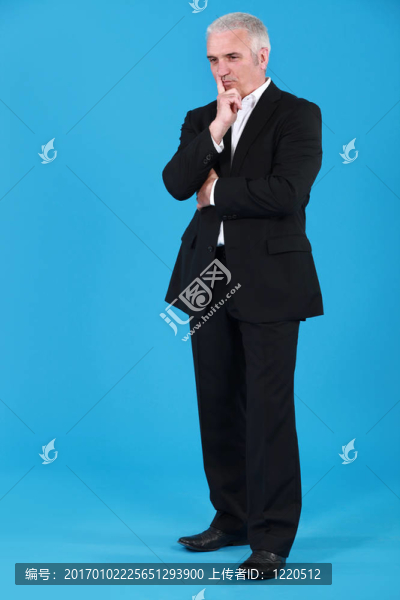 成熟的憂郁的商人拿手指放在嘴前的全身肖像
