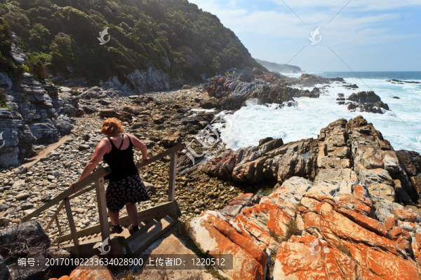 沿著巖石海岸徒步旅行的女子