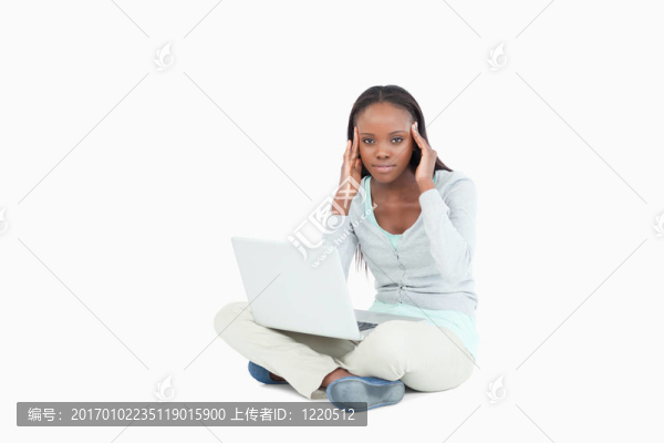 年輕女子坐在地板上，頭痛的筆記本電腦