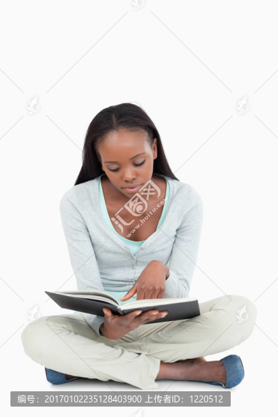 坐在地板上的年輕女人專注于她的書