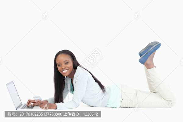 側(cè)面的女人躺在地板上與她的筆記本