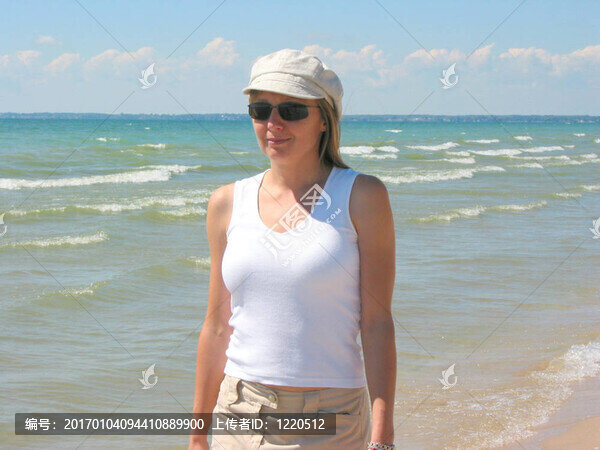 年輕的女人在海灘上散步