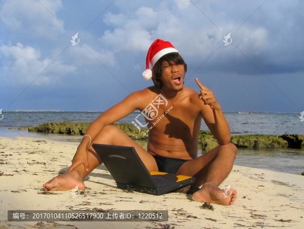 亞洲圣誕老人在沙灘上的筆記本電腦