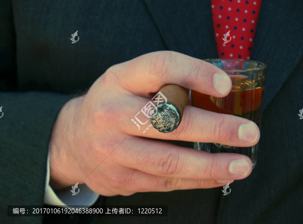 拿著一支雪茄和一杯威士忌的男人