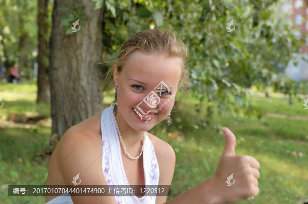 美麗的女孩坐在公園豎起大拇指
