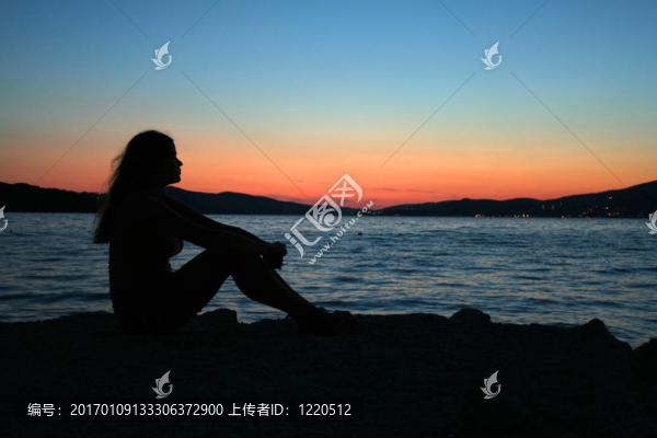 美麗的女人坐在沙灘上