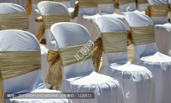 沙灘婚禮上帶金絲帶的白色椅子