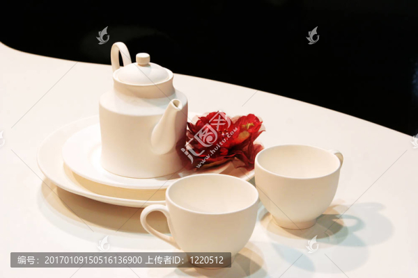白色的茶壺；杯碟與一朵紅色的花