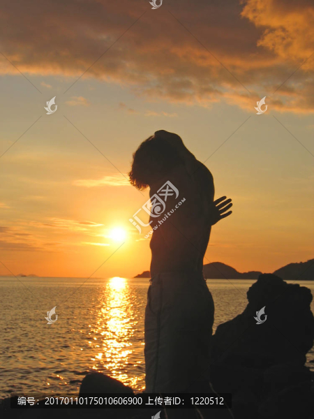 一個男人用奇怪的方式在夕陽下的海灘；納閩；有弗洛里斯島；印度尼西亞；