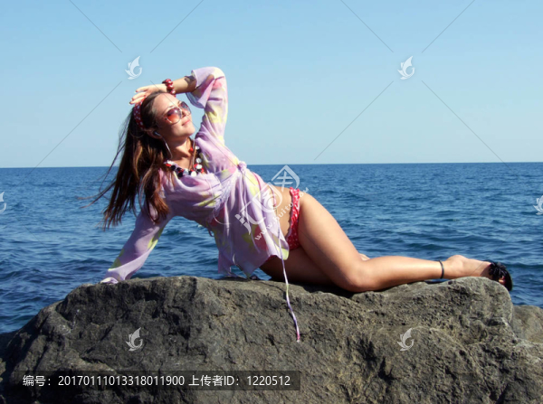 性女孩躺在巖石上，看著太陽