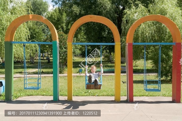 在城市公園里蕩秋千的小男孩