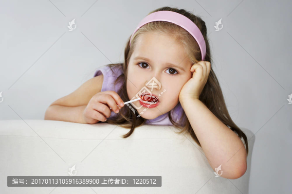 年輕漂亮的女孩在粉紅色背景光與棒棒糖