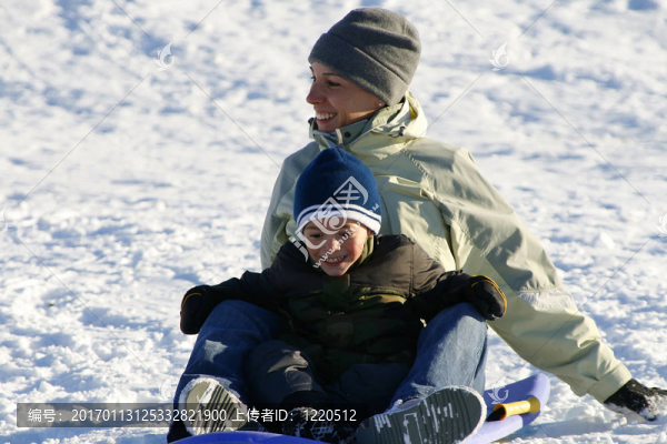 幸福的母親和兒子坐雪橇滑下Hill