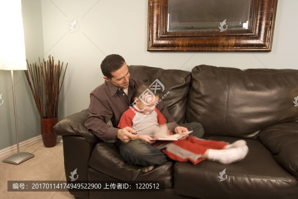 父親和兒子在沙發(fā)上讀一本書
