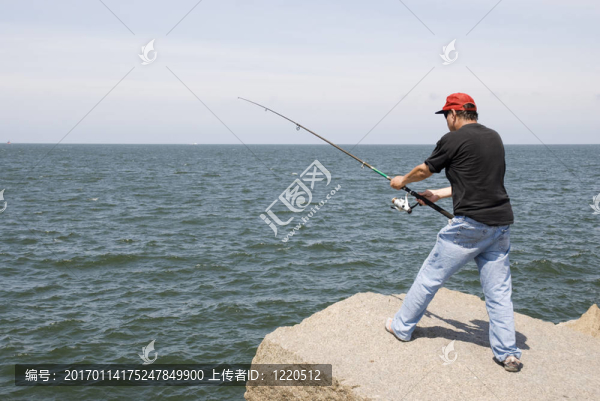 在巖石上釣魚的人