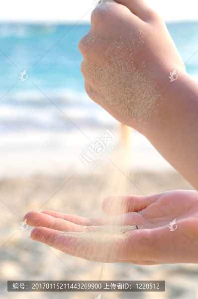 雙手在海灘上灌沙