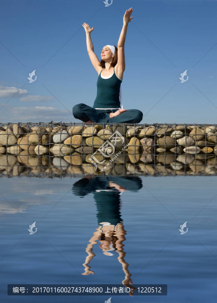 一個(gè)女人在水上的石頭上做瑜伽