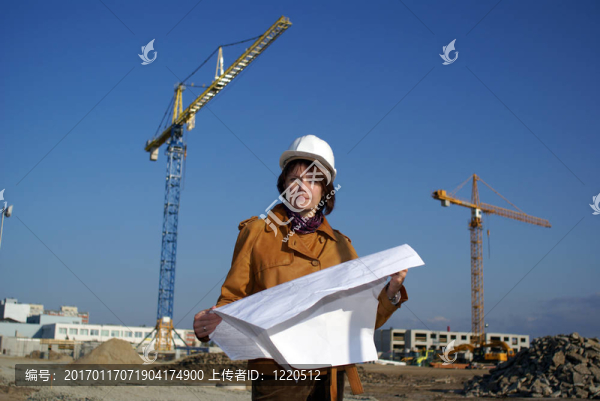 漂亮的女建筑師手持藍圖，站在建筑工地