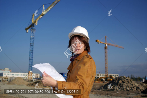 漂亮的女建筑師手持藍(lán)圖，站在建筑工地