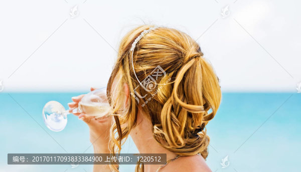 新娘帶著一杯香檳望著大海