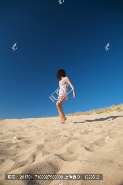 穿著的女人走在沙灘上