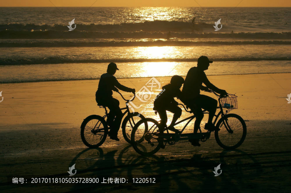 家庭在日落時分沿著海灘騎自行車。
