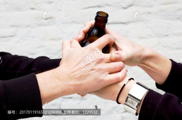 兩只手拿著一個深色玻璃瓶